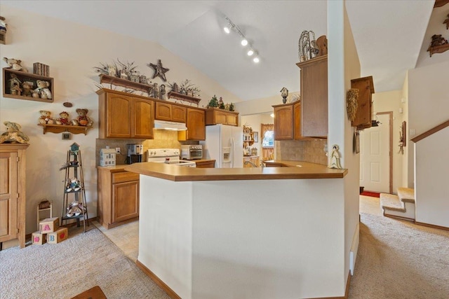 14316 E 31st Ln, Veradale, WA 99037 - kitchen with decorative backsplash, range with electric stovetop, lofted ceiling, white fridge with ice dispenser, and under cabinet range hood