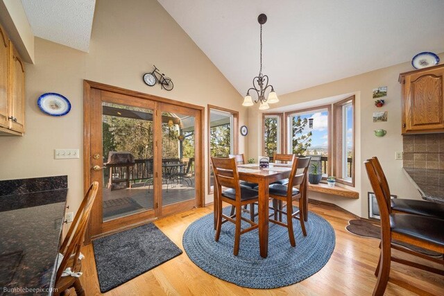 dining room featuring high vaulted ceiling, an inviting chandelier, and light wood finished floors