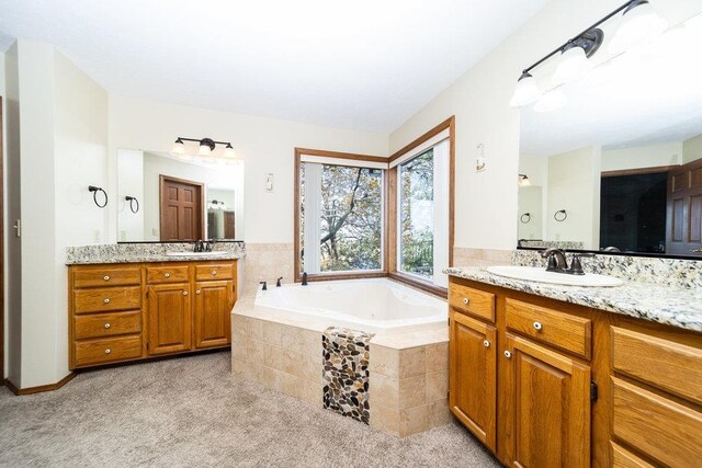 full bath with a sink, a garden tub, and two vanities