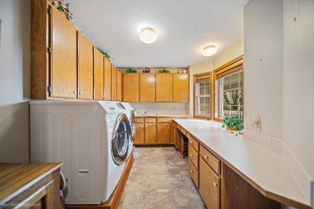 washroom featuring stone finish floor, a textured ceiling, cabinet space, a sink, and washer and clothes dryer