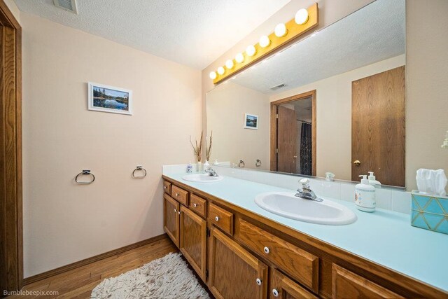 full bathroom featuring visible vents, a sink, wood finished floors, and double vanity