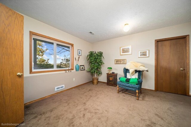 sitting room with carpet flooring, baseboards, and visible vents