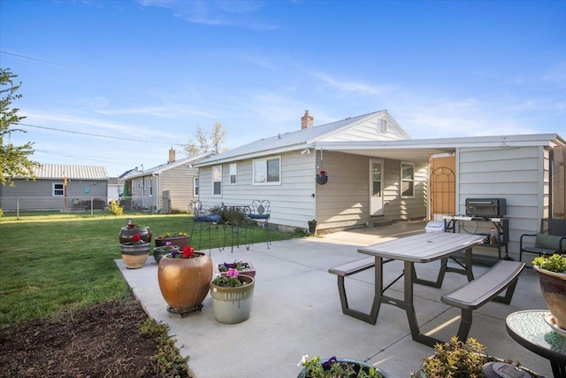 rear view of house with a lawn, fence, a chimney, and a patio area