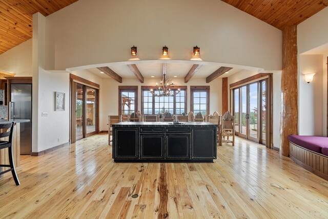 kitchen featuring dark cabinets, a center island with sink, light wood-style flooring, and a chandelier