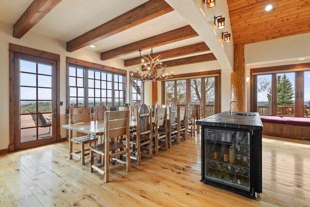 dining area with wine cooler, an inviting chandelier, beamed ceiling, and plenty of natural light