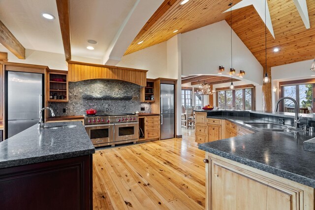 kitchen featuring a sink, high vaulted ceiling, a spacious island, and premium appliances