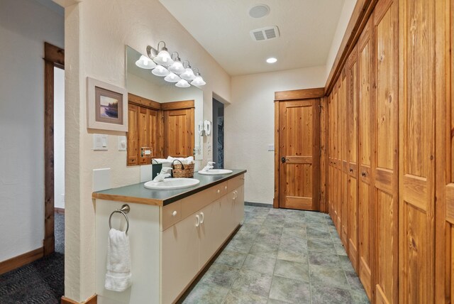 full bathroom with a sink, baseboards, double vanity, and visible vents