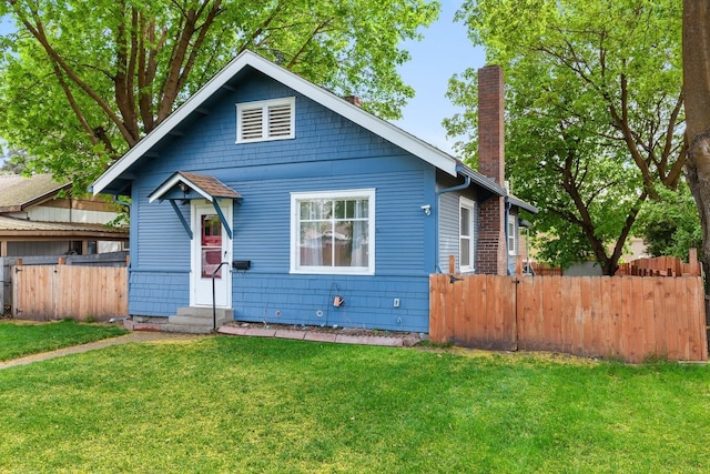 bungalow with entry steps, fence, a chimney, and a front yard