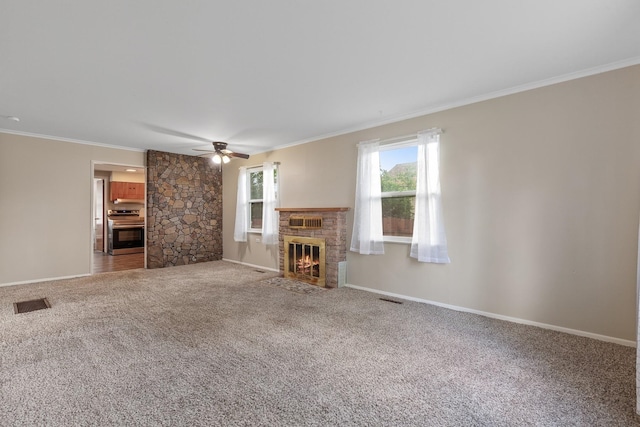 unfurnished living room featuring a ceiling fan, visible vents, crown molding, a fireplace, and carpet