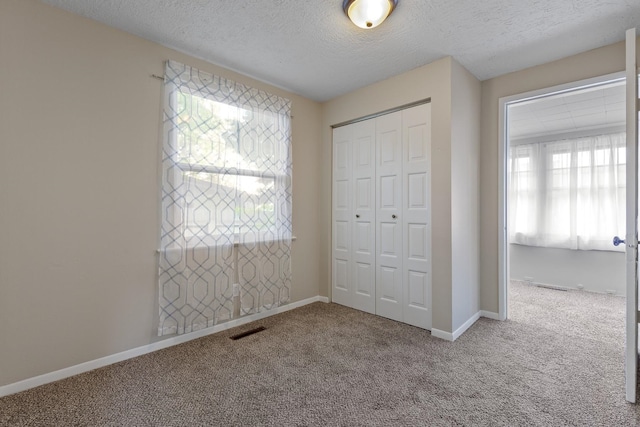 unfurnished bedroom with a closet, multiple windows, carpet flooring, and visible vents