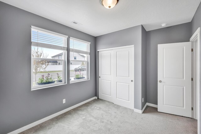 unfurnished bedroom with visible vents, carpet flooring, baseboards, and a closet