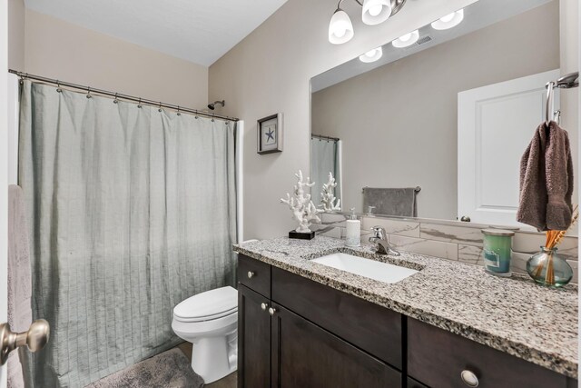 full bath featuring toilet, curtained shower, and vanity