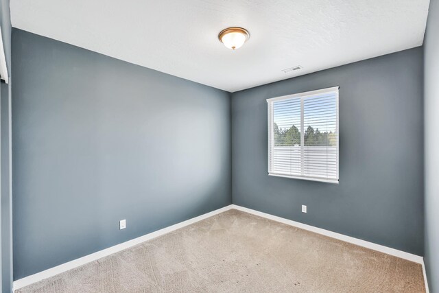 carpeted spare room with baseboards and visible vents