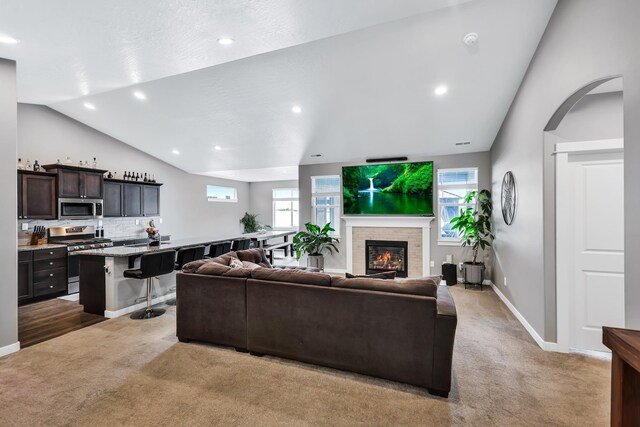 carpeted living room with a glass covered fireplace, baseboards, recessed lighting, and lofted ceiling