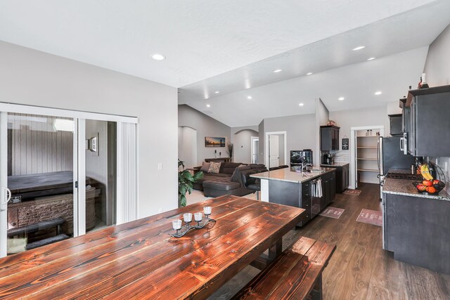 dining space with recessed lighting, arched walkways, vaulted ceiling, and dark wood finished floors