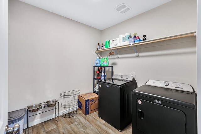 clothes washing area featuring separate washer and dryer, laundry area, and light wood-style floors