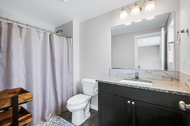 bathroom featuring vanity, toilet, baseboards, curtained shower, and wood finished floors