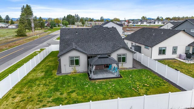 rear view of house with a gazebo, a residential view, a fenced backyard, and roof with shingles