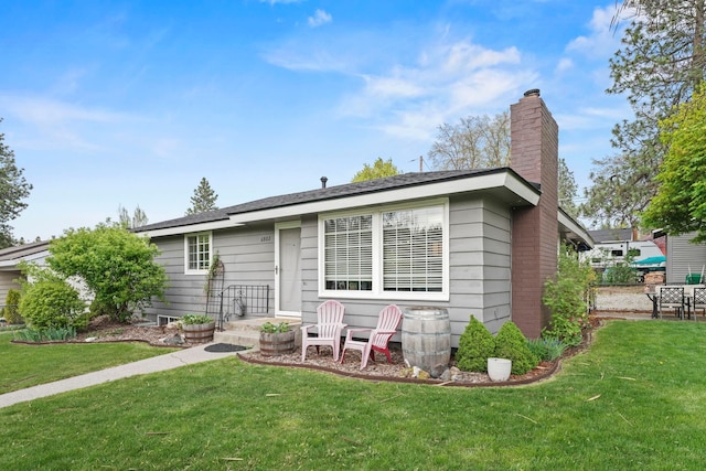 view of front of house with a chimney and a front lawn
