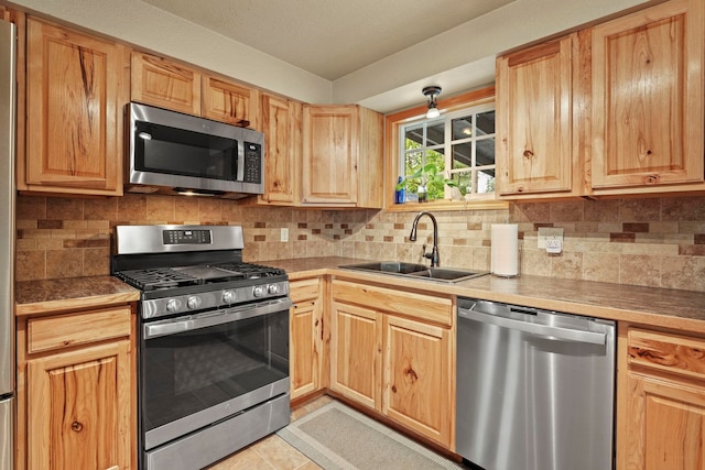 kitchen featuring a sink, appliances with stainless steel finishes, light brown cabinets, and tasteful backsplash