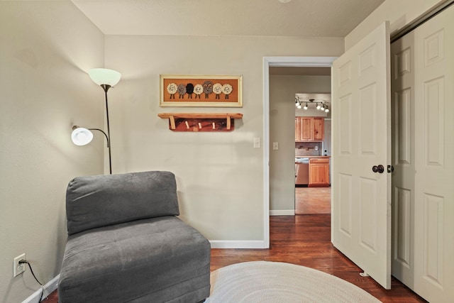 living area featuring baseboards, dark wood-style floors, and rail lighting