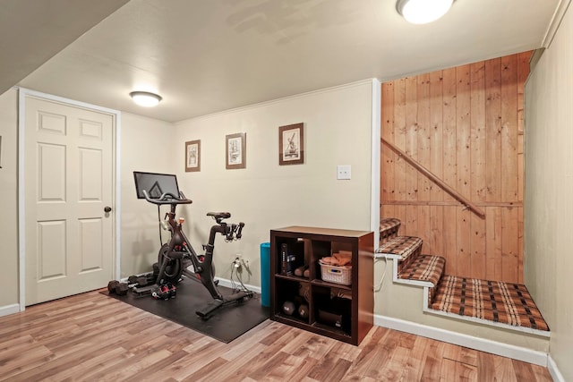 exercise area featuring wooden walls, baseboards, and wood finished floors