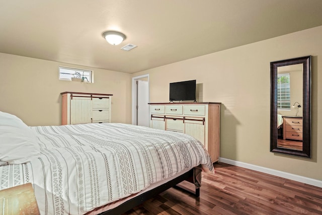 bedroom featuring baseboards, multiple windows, wood finished floors, and visible vents