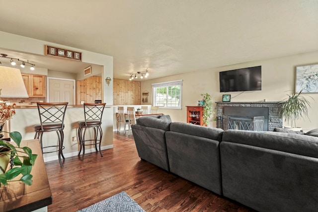 living area featuring track lighting, a fireplace, wood finished floors, and visible vents