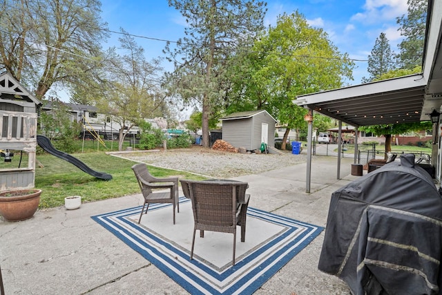 view of patio / terrace with an outbuilding, fence, a playground, a storage unit, and a grill