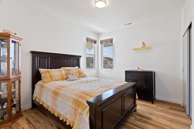 bedroom with baseboards, a closet, light wood-style flooring, and visible vents