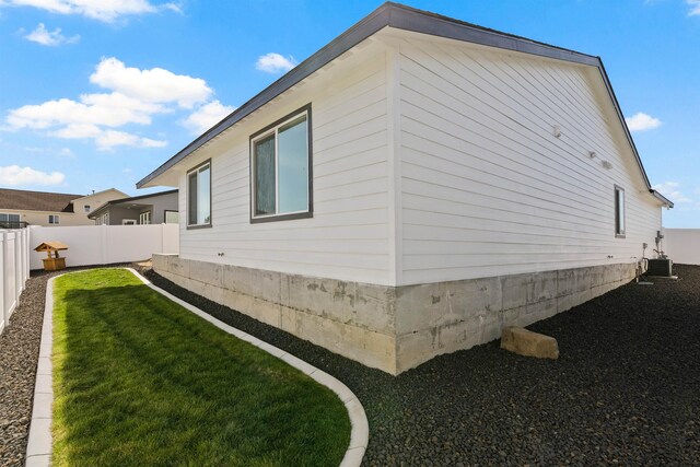 view of side of home with a lawn, fence, and central air condition unit
