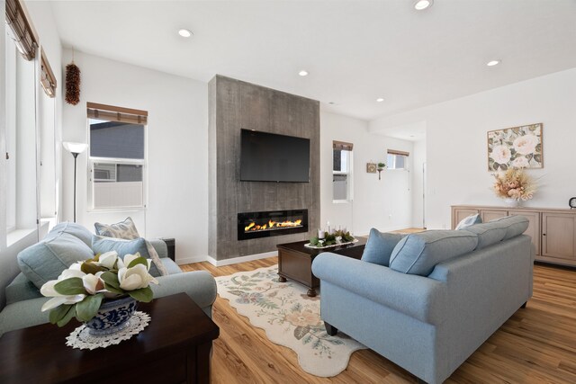 living area with recessed lighting, a large fireplace, and wood finished floors