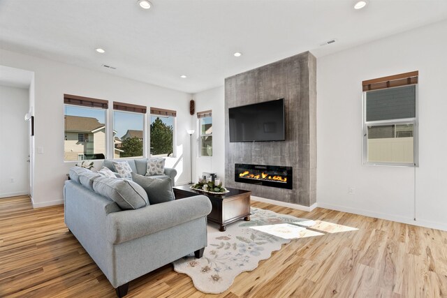 living room featuring a tiled fireplace, recessed lighting, and wood finished floors