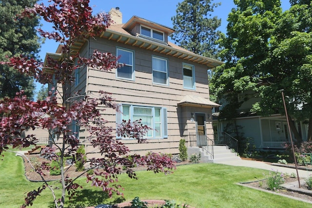 american foursquare style home with a chimney and a front lawn