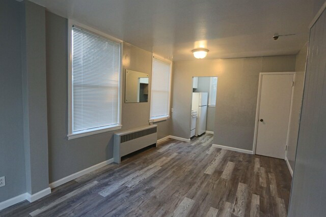 unfurnished room with baseboards, radiator heating unit, and wood finished floors