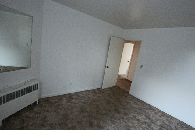 unfurnished bedroom featuring baseboards, carpet, and radiator heating unit