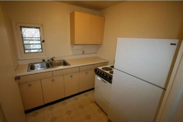 kitchen with a sink, light countertops, white appliances, and light floors