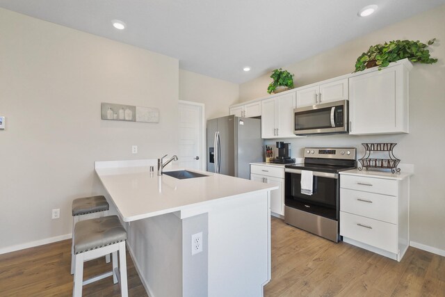 kitchen featuring a sink, white cabinets, a breakfast bar, and stainless steel appliances