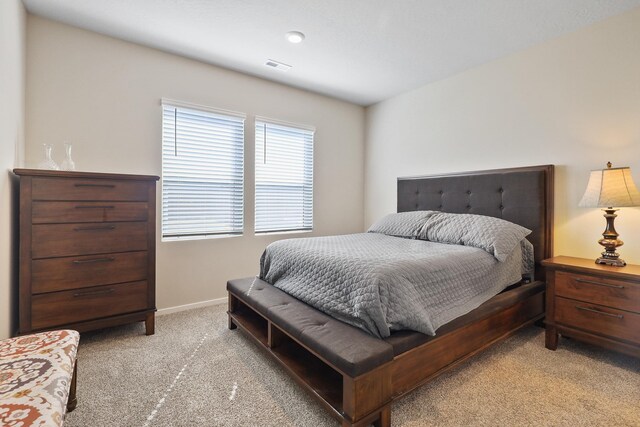 bedroom with visible vents, baseboards, and light carpet