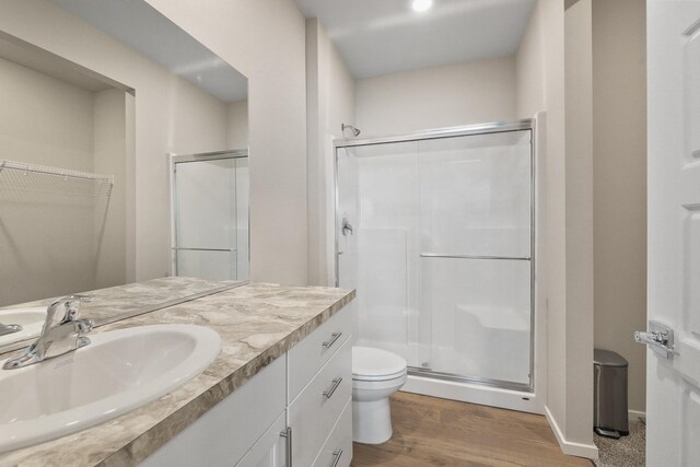 full bath featuring vanity, a stall shower, toilet, and wood finished floors