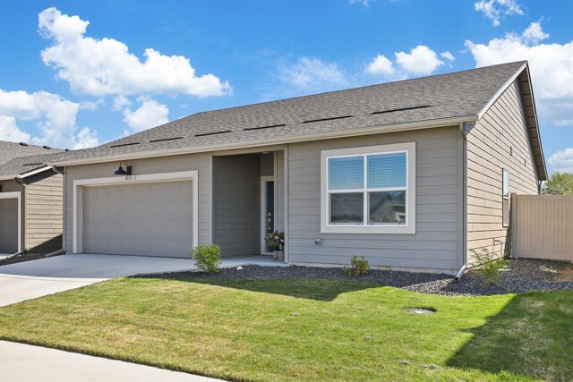 ranch-style house featuring a garage, fence, concrete driveway, and a front yard