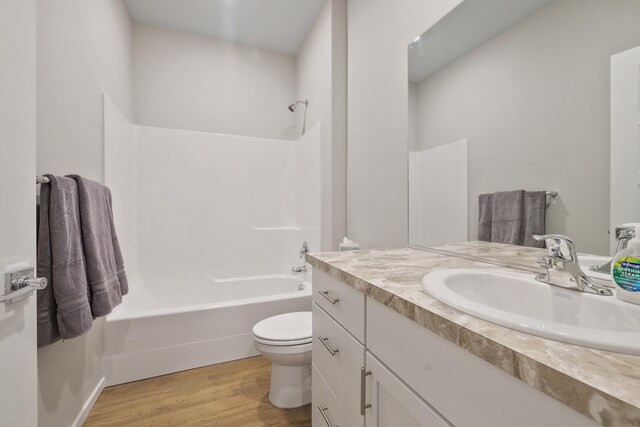 bathroom featuring vanity, wood finished floors, bathing tub / shower combination, and toilet
