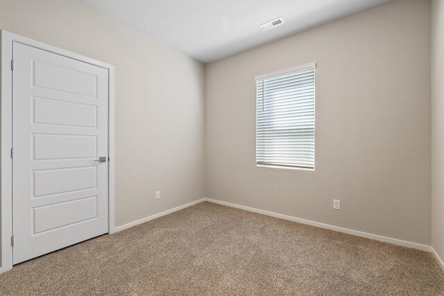 spare room featuring carpet floors, baseboards, and visible vents