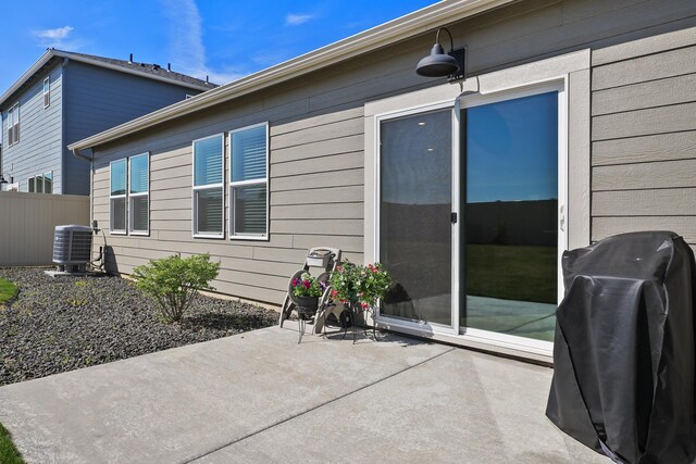 rear view of house featuring fence, central AC unit, and a patio area