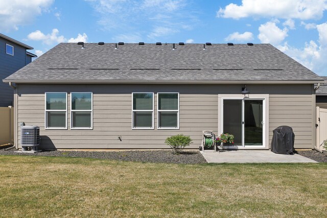 rear view of house featuring roof with shingles, a patio, a yard, and cooling unit