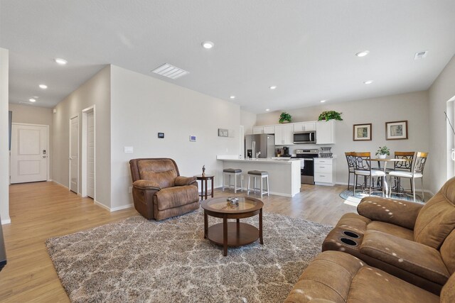 living area featuring recessed lighting, baseboards, and light wood-style floors