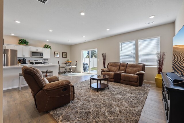 living room with light wood-style floors, recessed lighting, and visible vents
