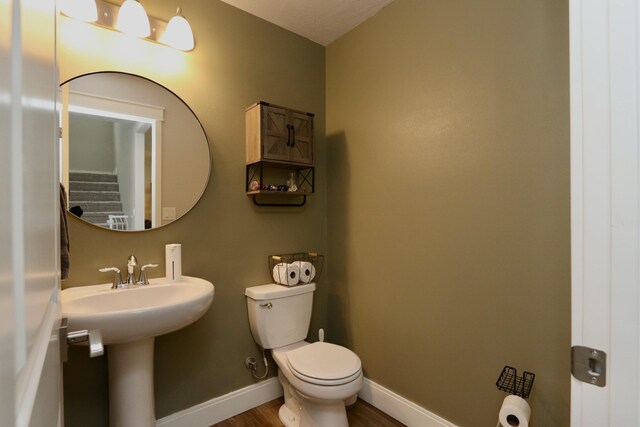 bathroom with baseboards, wood finished floors, and toilet