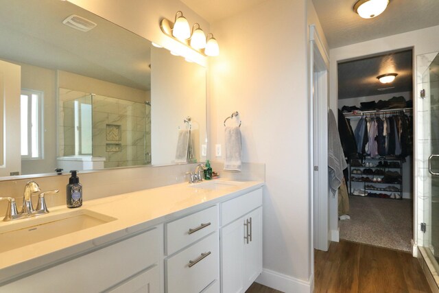 bathroom with a sink, a walk in closet, a stall shower, and wood finished floors