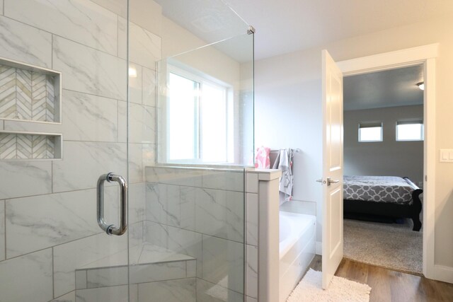 ensuite bathroom with a shower stall, wood finished floors, a bath, and ensuite bath